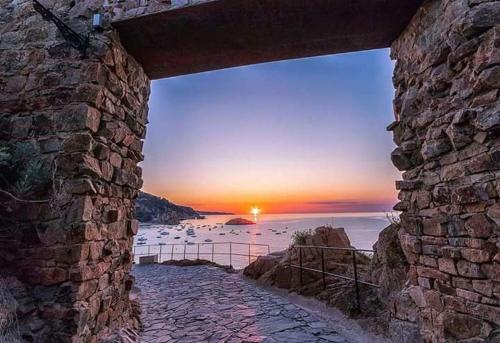 - une vue sur le coucher de soleil depuis un mur en pierre dans l'établissement Portal 17 Can Tort, à Tossa de Mar