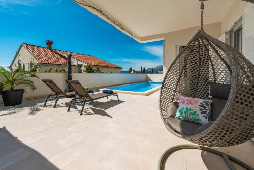 a swinging hammock on a patio with a swimming pool at Deluxe Apartment Unique-With Private Heated Pool in Cavtat