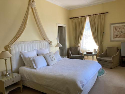 a bedroom with a large white bed and two chairs at Faversham House in York