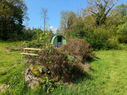 a green cabin in the middle of a field at MotoCamp Wales -Camping Pods in Dolgellau
