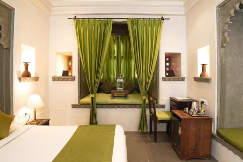 een slaapkamer met een bed en een raam met groene gordijnen bij Madri Haveli in Udaipur
