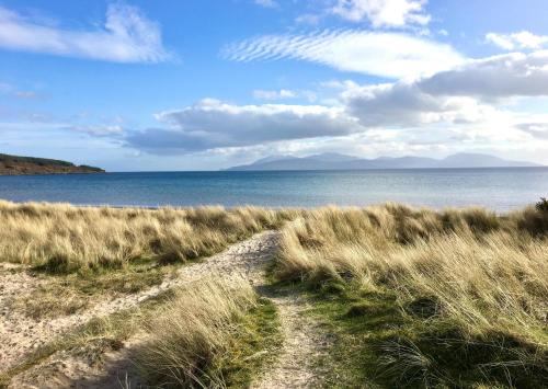 a path through a field of grass next to the water at Craignethan in Kames