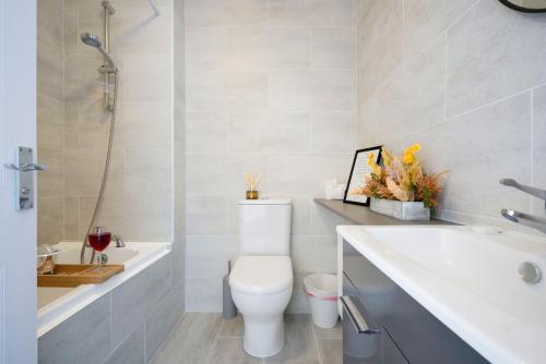 a bathroom with a toilet and a tub and a sink at Stylish House - Close to City Centre and Luton Airport - Free Parking, Super-Fast Wifi, Garden and Smart TV with Netflix by Yoko Property in Luton