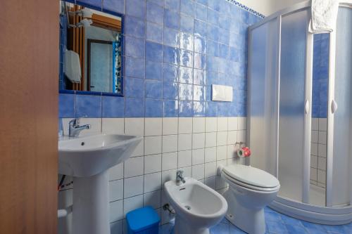 bagno piastrellato blu con servizi igienici e lavandino di Le Cale a Lampedusa