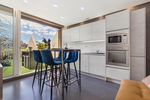 une cuisine avec des placards blancs et des tabourets de bar bleus dans l'établissement Sex and the city Heliopolis, au Cap d'Agde