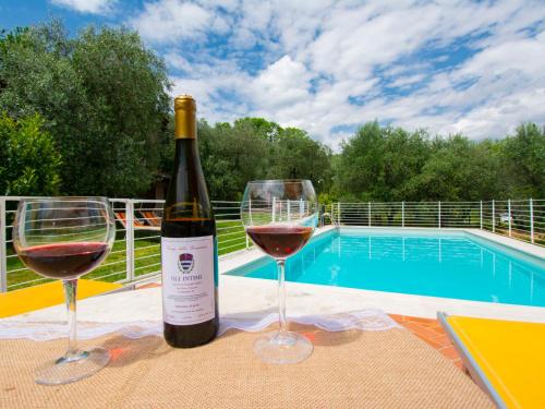 two glasses of wine sitting on a table near a pool at Holiday Home Colle alla luna by Interhome in Pieve a Nievole