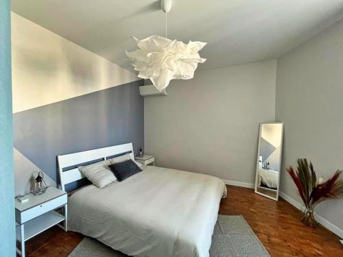 ein Schlafzimmer mit einem weißen Bett und einem Kronleuchter in der Unterkunft Chato D-Charmant T2 Moderne et Calme in Châteaurenard
