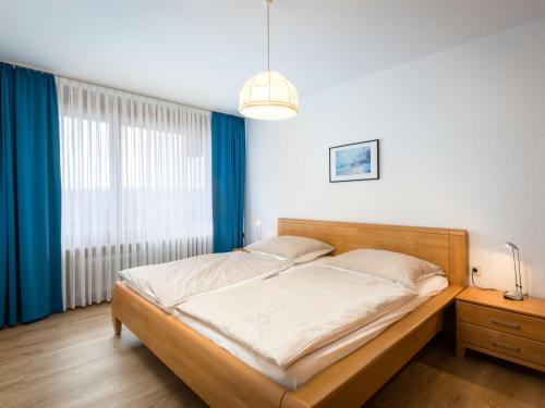 Schlafzimmer mit einem Bett und einem Fenster mit blauen Vorhängen in der Unterkunft Apartment A701 by Interhome in Lahnstein