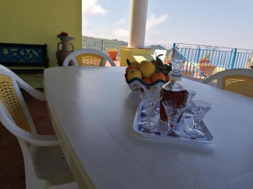 un tavolo con un cesto di frutta, una bottiglia e bicchieri di Villa Panorama a Città di Lipari