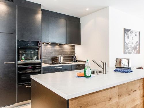 eine Küche mit schwarzen Schränken und einer weißen Arbeitsplatte in der Unterkunft Apartment TITLIS Resort 3-Zimmer Familienwohnung 1 in Engelberg