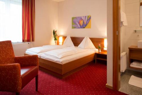 Schillerhof Hotel GARNI في فوكلابروك: غرفه فندقيه بسرير وكرسي