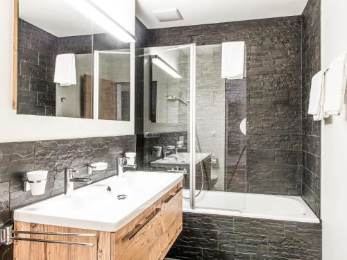 ein Badezimmer mit einem Waschbecken, einer Dusche und einer Badewanne in der Unterkunft Apartment TITLIS Resort 2-Zimmer Wohnung 2 by Interhome in Engelberg