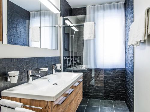 een badkamer met een wastafel en een douche bij Apartment TITLIS Resort 4-Zimmer Wohnung 1 by Interhome in Engelberg