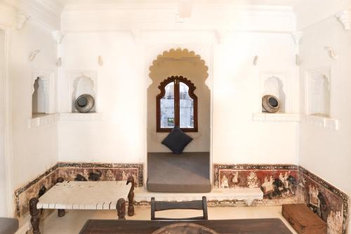 um quarto com uma mesa e uma janela em Madri Haveli em Udaipur