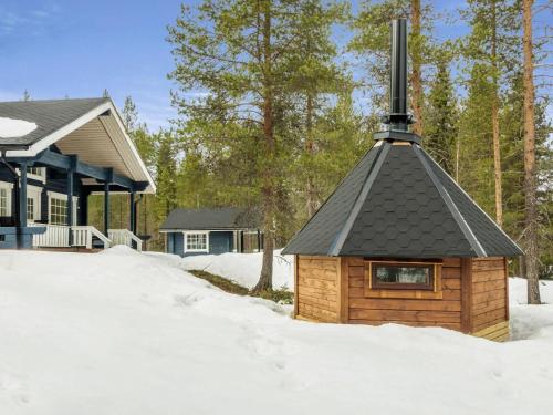 uma igreja de madeira com um telhado preto na neve em Holiday Home Keselmäkangas by Interhome em Tikkala