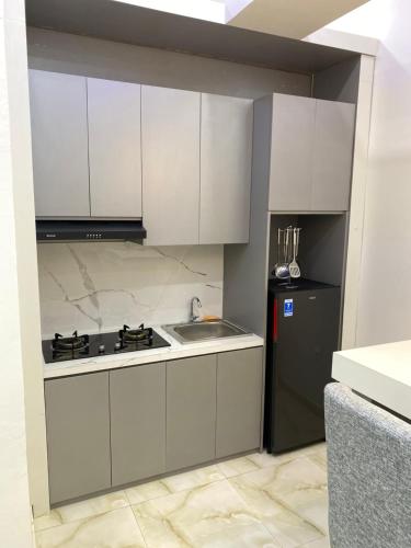 a kitchen with white cabinets and a sink and a refrigerator at Algara Puncak Hotel in Puncak