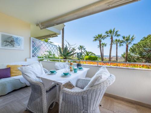 une table et des chaises blanches sur un balcon avec des palmiers dans l'établissement Apartment Alexandra Palace-4 by Interhome, à Cannes