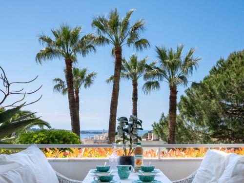 une table avec des assiettes de nourriture sur un balcon avec des palmiers dans l'établissement Apartment Alexandra Palace-4 by Interhome, à Cannes