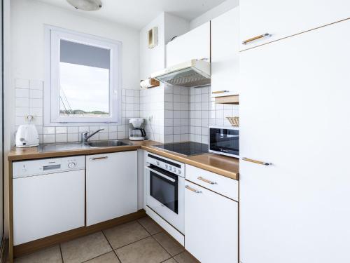 eine Küche mit weißen Schränken und einem Fenster in der Unterkunft Apartment Les Quais de L'Amirauté-8 by Interhome in Saint Cyprien Plage