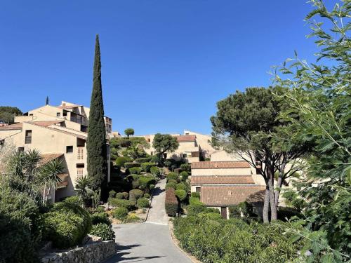 un chemin à travers un jardin planté d'arbres et de bâtiments dans l'établissement Appartement 3 pièces climatisé avec piscine, tennis, parking à La Croix-Valmer - FR-1-226B-152, à La Croix-Valmer