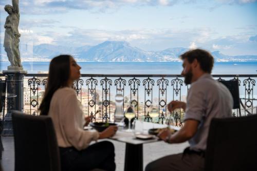zwei Personen sitzen an einem Tisch mit Meerblick in der Unterkunft Grand Hotel Parker's in Neapel