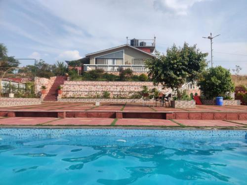 una casa con piscina frente a una casa en Hilltop Resort and Agro Tourism Wai, Near Panchgani en Wai