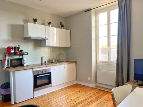 Elle comprend une petite cuisine avec des placards blancs et une fenêtre. dans l'établissement Claire - Bel Appartement T2 Lumineux, à Châteaurenard