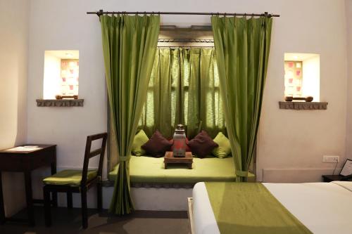 a bedroom with a bed and a window with green curtains at Madri Haveli in Udaipur