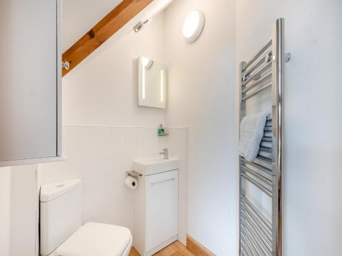 uma casa de banho branca com um WC e um espelho. em Mill Barn em Torbeg