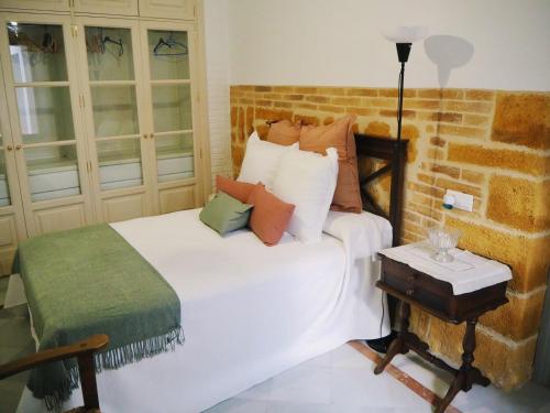 una camera con un letto bianco e un muro di mattoni di Carmona Center Apartment a Carmona
