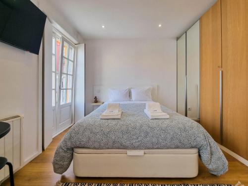 a bedroom with a large bed with two towels on it at SAM - Studio in the city center in Viana do Castelo