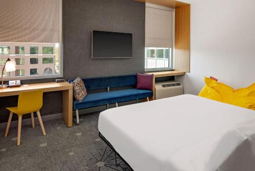 Habitación de hotel con cama, escritorio y TV. en Aloft Chapel Hill, en Chapel Hill