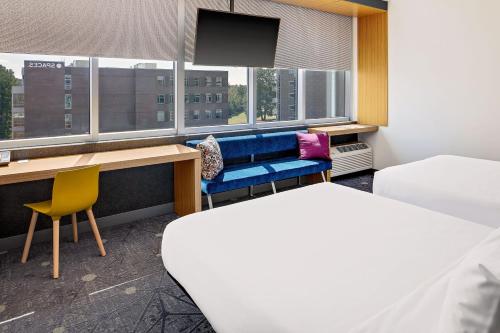 a room with a blue bench and a desk and window at Aloft Chapel Hill in Chapel Hill