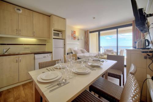 une cuisine avec une table avec des assiettes et des verres à vin dans l'établissement IMMOGROOM - 2BR - sea view - Swimming pool - Terrace - Parking - AC - Wifi, à Cannes