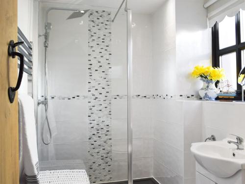 een witte badkamer met een douche en een wastafel bij Sweet Pea Cottage in Llanelli