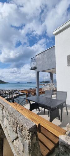 a table and benches on a patio near the beach at Private Villa by the sea in Žuljana