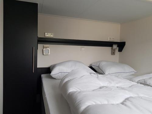2 camas en una habitación con sábanas y almohadas blancas en De Bijsselse Enk, Noors chalet 19, en Nunspeet