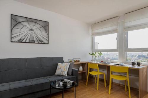 een woonkamer met een bank, een tafel en gele stoelen bij StarterApart Wrocław - MAMY WOLNE POKOJE ! in Wrocław