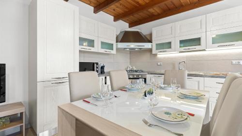 a kitchen with a white table and chairs and a kitchen with white cabinets at Sardinianworld - Casa S'Architteddu in Putzu Idu