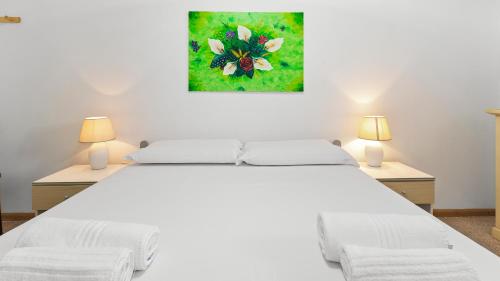 a bedroom with a large white bed with two lamps at Sardinianworld - Casa S'Architteddu in Putzu Idu
