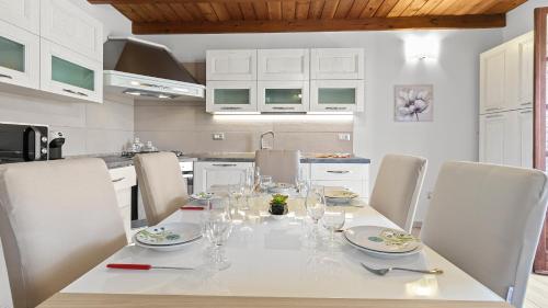 a dining room table with chairs and a white kitchen at Sardinianworld - Casa S'Architteddu in Putzu Idu