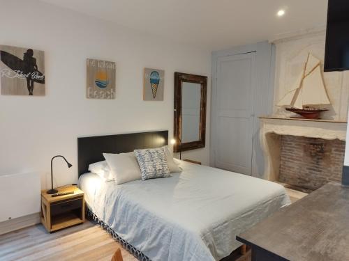 - une chambre avec un lit blanc et une cheminée dans l'établissement Le St Louis Chambre aménagée avec cuisine N°4, à La Rochelle