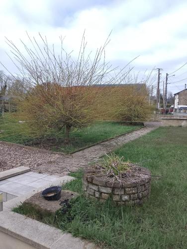 a garden with a tree and a stone wall at Chez Claude in Rimogne