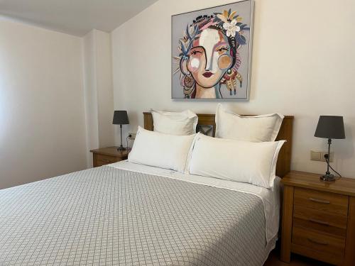 1 dormitorio con 1 cama con almohadas blancas y una pintura en Casa O Muiño, en Poio