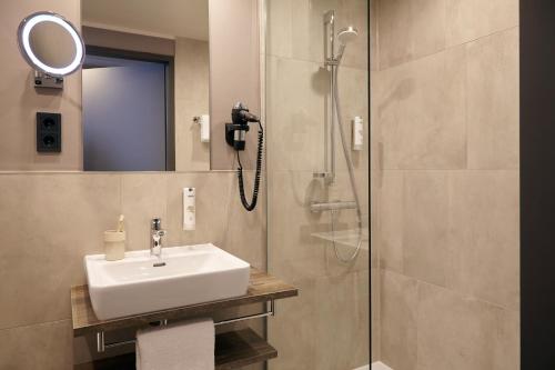 ein Bad mit einem Waschbecken und einer Dusche in der Unterkunft acora Düsseldorf Airport Living the City - Apartments in Düsseldorf
