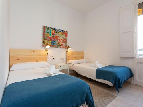 a room with two beds with blue and white sheets at Centric Sagrada Familia Apartments in Barcelona