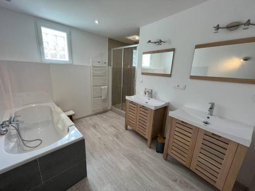 a large bathroom with two sinks and a tub and a tub at Opale YourHostHelper in Luc-sur-Mer
