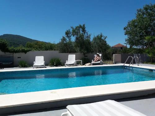 a woman sitting in a chair next to a swimming pool at Apartments Villa Dona in Vela Luka