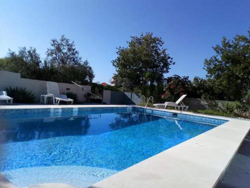 a swimming pool with two lawn chairs next to it at Apartments Villa Dona in Vela Luka