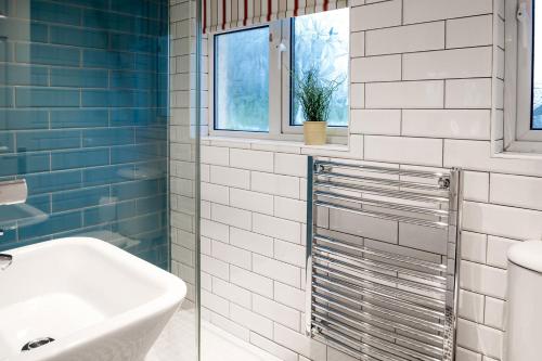 a bathroom with blue and white tiles and a sink at Bosinver Farm Cottages Well Close in St Austell